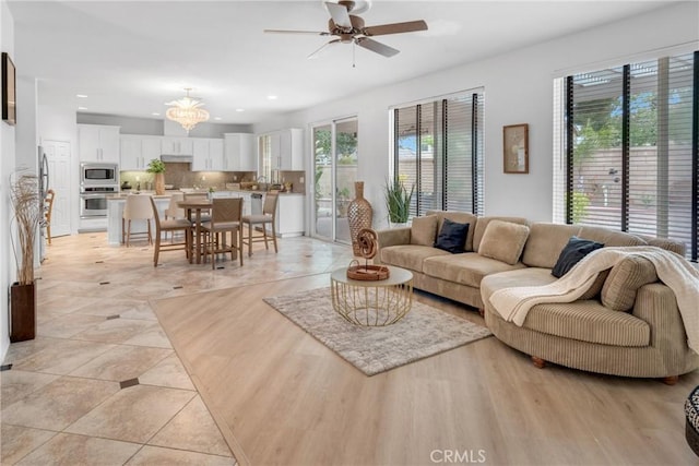 living room featuring plenty of natural light, recessed lighting, and ceiling fan with notable chandelier