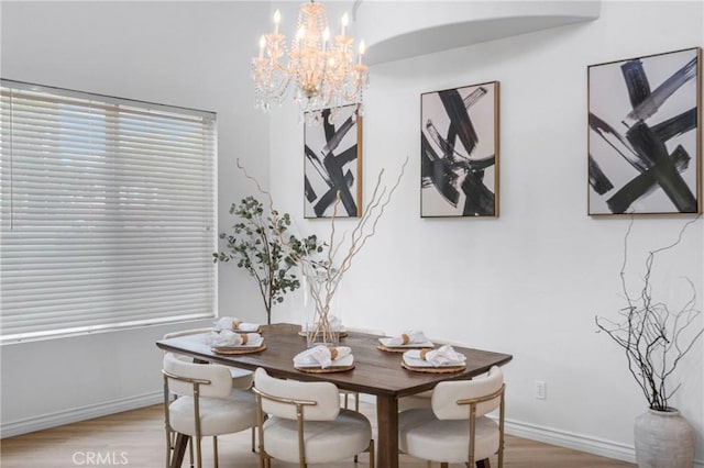 dining space with baseboards, light wood-style flooring, and a notable chandelier