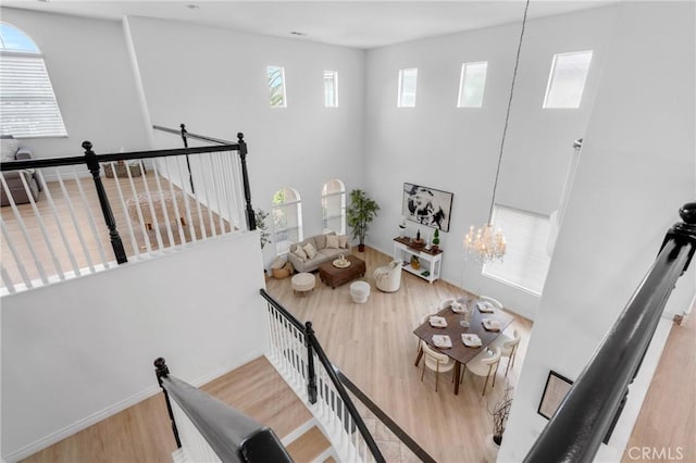 dining space featuring baseboards, a high ceiling, wood finished floors, and a notable chandelier