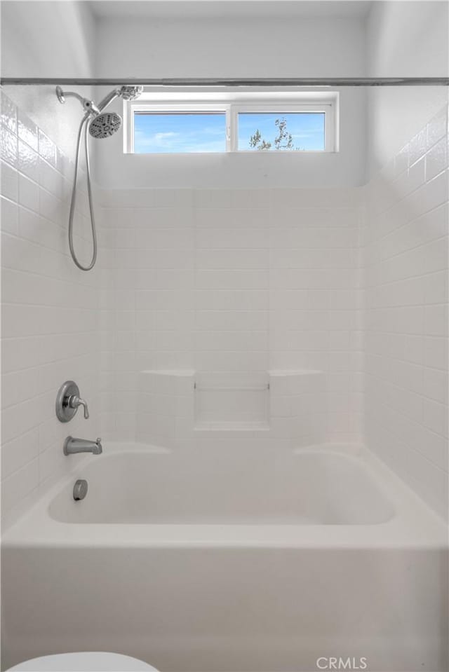 full bath with tub / shower combination, toilet, and a wealth of natural light