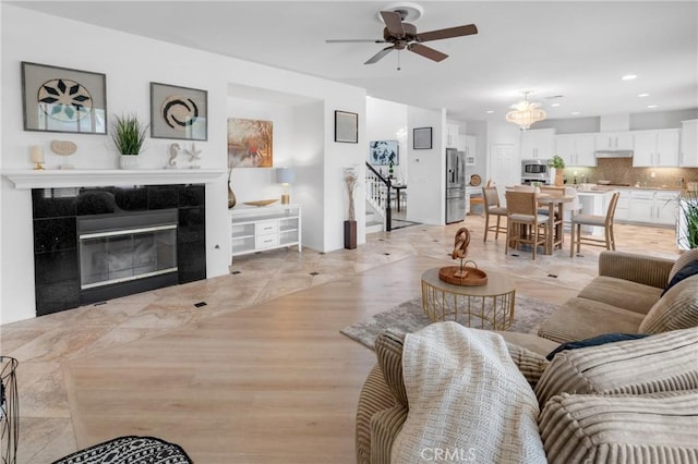 living room featuring ceiling fan, a fireplace, light wood-style flooring, stairs, and recessed lighting