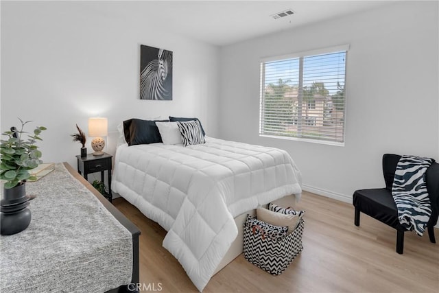 bedroom with baseboards, visible vents, and light wood-type flooring