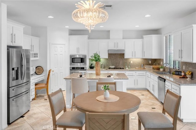 kitchen with white cabinets, appliances with stainless steel finishes, and decorative backsplash