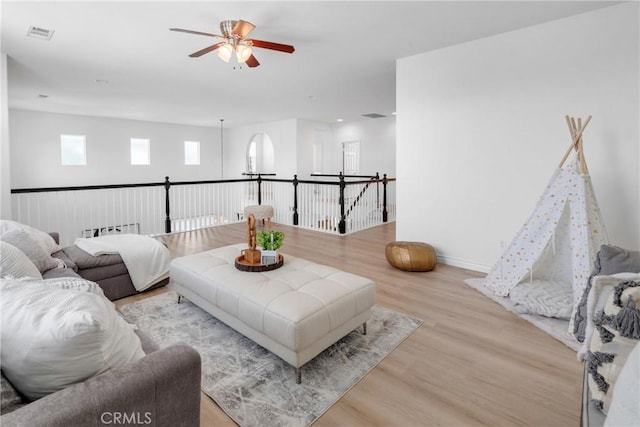 living room with baseboards, a ceiling fan, wood finished floors, and visible vents