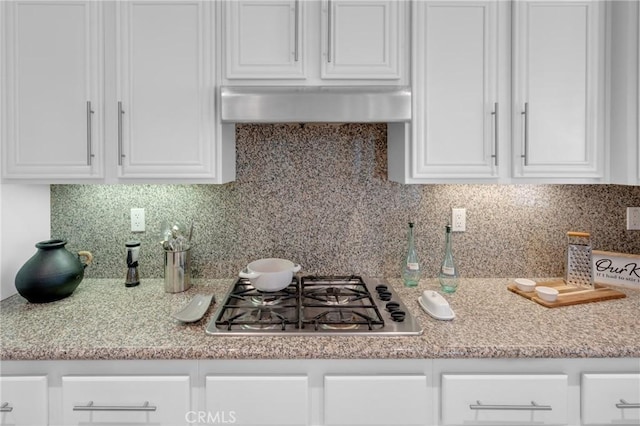 kitchen with stainless steel gas stovetop, under cabinet range hood, and white cabinetry