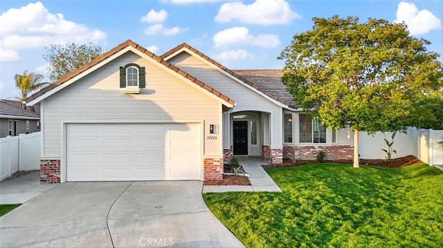 view of front of house with a front lawn, a garage, driveway, brick siding, and fence