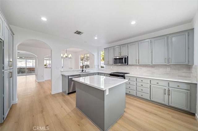 kitchen with visible vents, gray cabinets, stainless steel appliances, and arched walkways