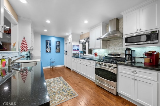 24848 Matterhorn Ct, Crestline, CA 92325 - kitchen featuring stainless steel appliances, backsplash, a sink, white cabinetry, and wall chimney exhaust hood