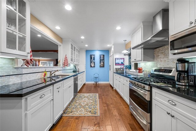 24848 Matterhorn Ct, Crestline, CA 92325 - kitchen with tasteful backsplash, a sink, appliances with stainless steel finishes, baseboards, and wall chimney exhaust hood