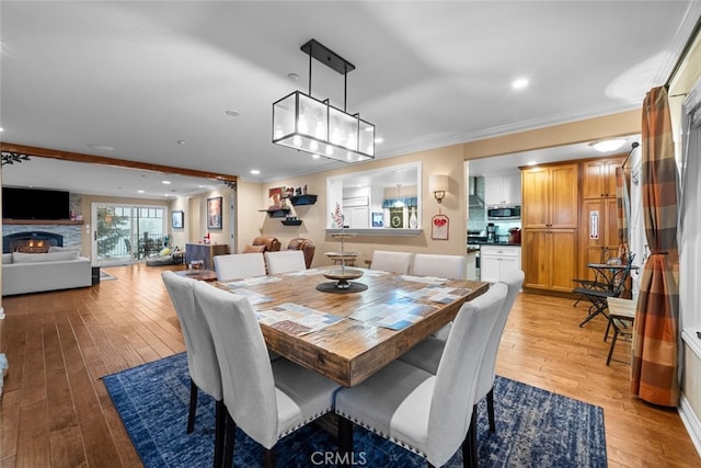 24848 Matterhorn Ct, Crestline, CA 92325 - dining area featuring a fireplace, light wood-style floors, recessed lighting, and ornamental molding