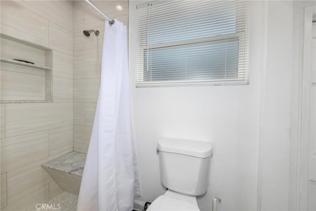 full bathroom featuring toilet and tiled shower