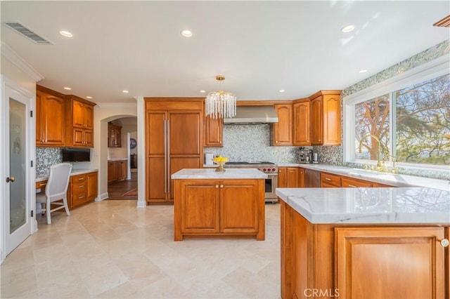 kitchen featuring tasteful backsplash, wall chimney exhaust hood, visible vents, arched walkways, and high end stainless steel range oven