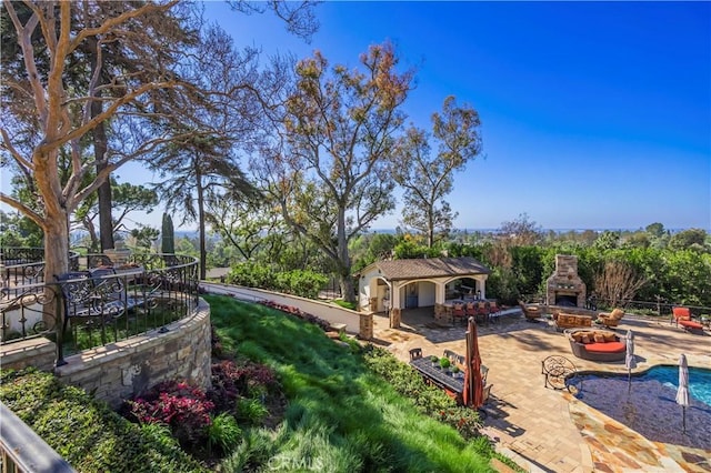 exterior space featuring a patio, an outdoor stone fireplace, and fence