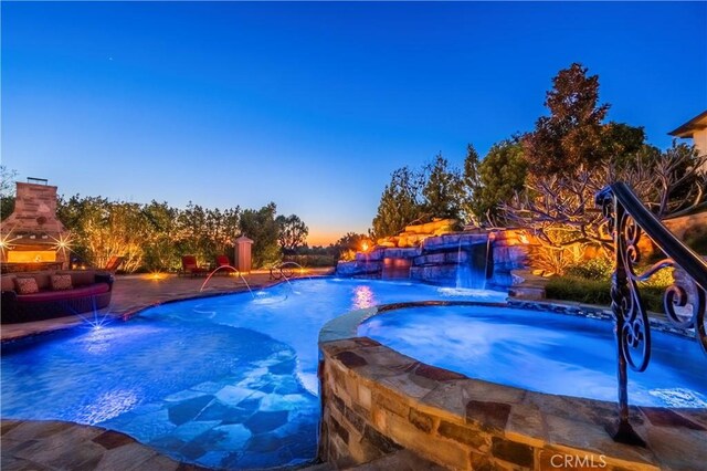 view of pool featuring a patio, a pool with connected hot tub, and a fireplace