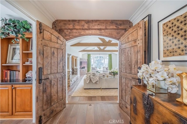 hallway with wood finished floors, crown molding, and arched walkways