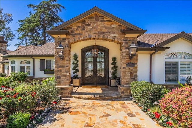 property entrance featuring french doors, stucco siding, and stone siding