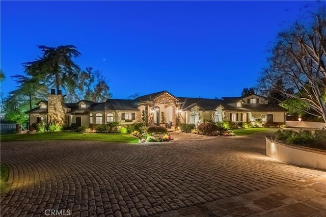 mediterranean / spanish-style house with curved driveway, stucco siding, and a front yard