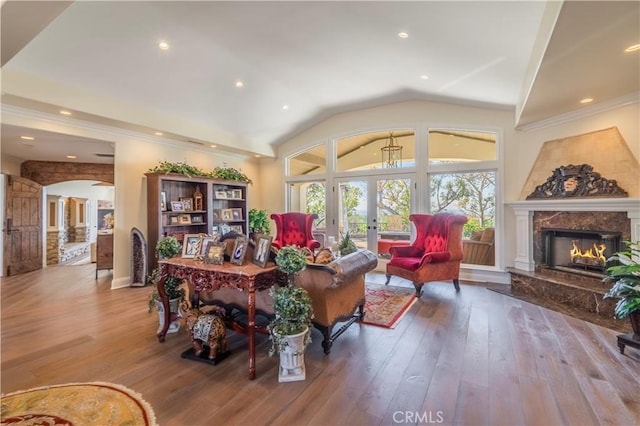 living area featuring hardwood / wood-style floors, arched walkways, french doors, and a fireplace