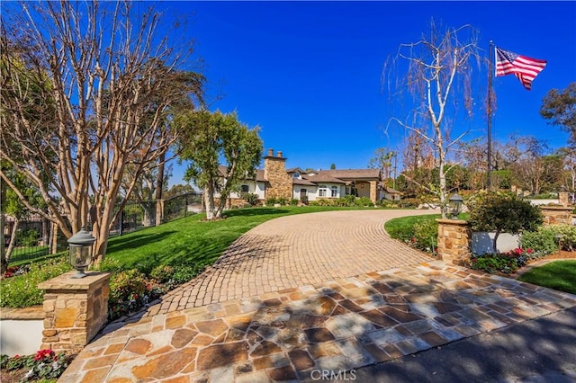 view of front of house with a front yard, curved driveway, and fence