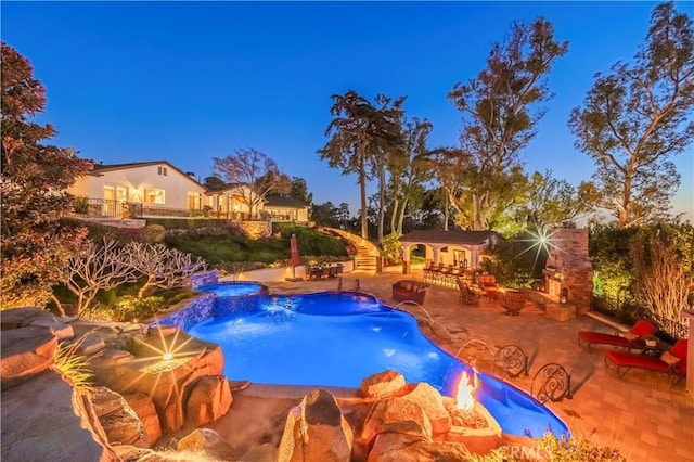pool featuring a patio, an outdoor structure, an exterior structure, and an in ground hot tub