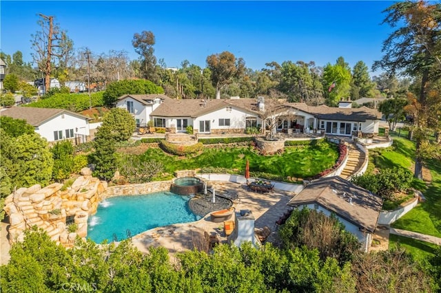 exterior space featuring a pool with connected hot tub and a patio area