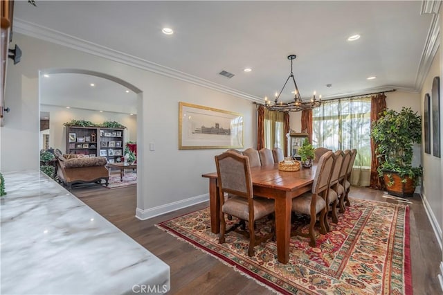 dining area featuring a chandelier, dark wood-type flooring, crown molding, visible vents, and arched walkways