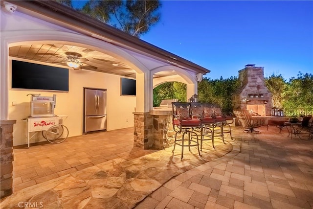 view of patio featuring outdoor dry bar, ceiling fan, and an outdoor stone fireplace