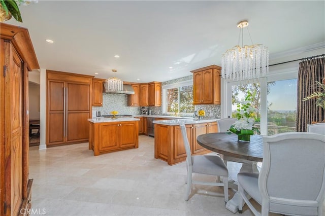 kitchen featuring tasteful backsplash, light countertops, a notable chandelier, and brown cabinetry
