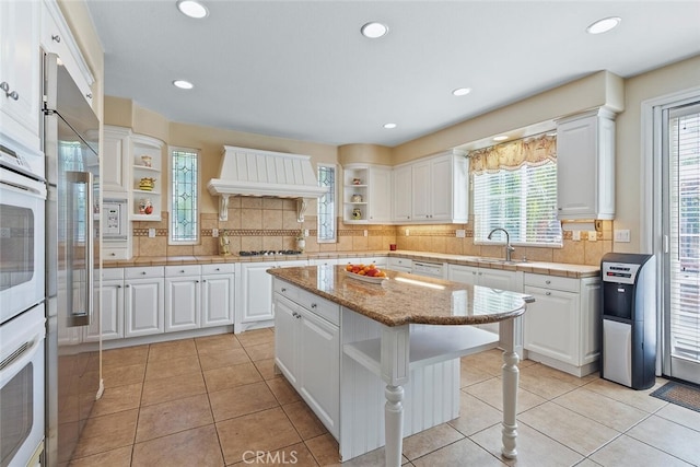 28 Malibu, Irvine, CA 92602 - kitchen with open shelves, custom range hood, white cabinetry, decorative backsplash, and recessed lighting