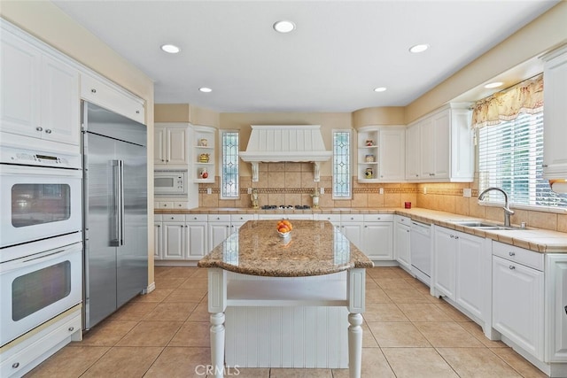 28 Malibu, Irvine, CA 92602 - kitchen with open shelves, built in appliances, premium range hood, white cabinets, and recessed lighting