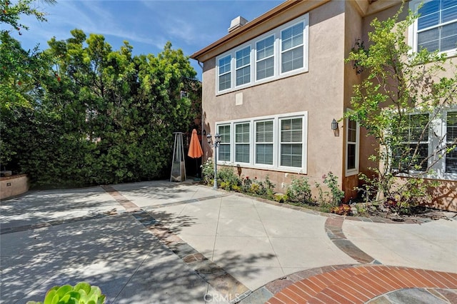 28 Malibu, Irvine, CA 92602 - view of side of home featuring stucco siding, a patio, and a chimney