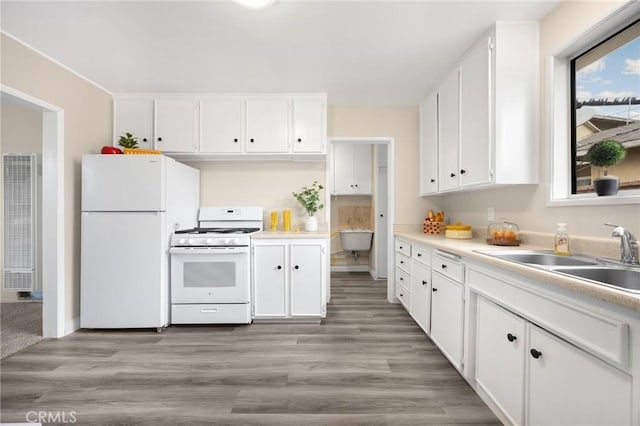 kitchen with a heating unit, a sink, white cabinetry, and white appliances