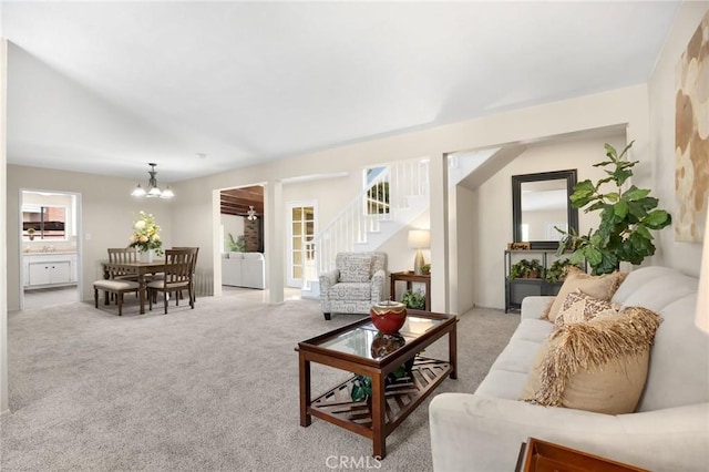 living room with stairs, an inviting chandelier, and light colored carpet