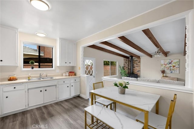 kitchen featuring white cabinetry, a wood stove, light wood-style floors, and a sink