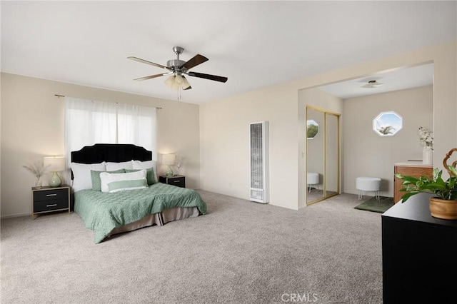 carpeted bedroom with a heating unit and a ceiling fan
