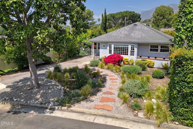 exterior space with a mountain view, fence, stucco siding, and roof with shingles