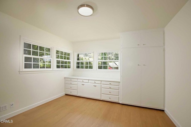 kitchen with white cabinetry, light countertops, light wood finished floors, and baseboards