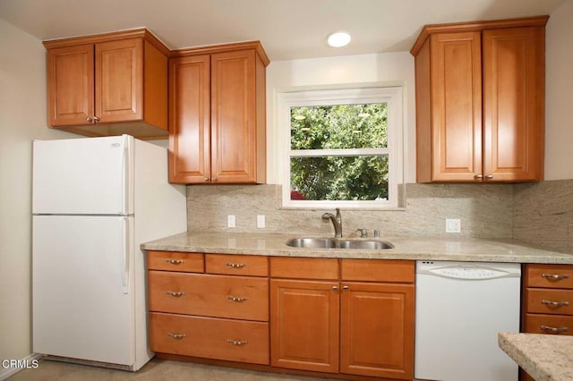 kitchen featuring brown cabinets, white appliances, and a sink