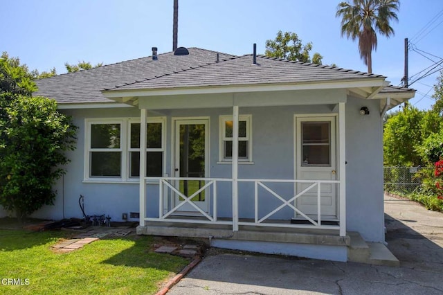 back of property with fence, stucco siding, and a yard