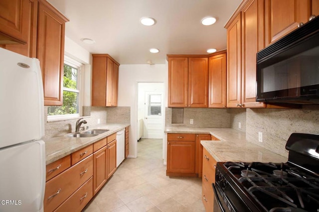 kitchen featuring light stone counters, tasteful backsplash, a sink, black appliances, and recessed lighting