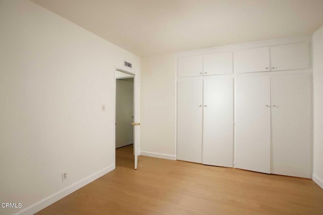 unfurnished bedroom featuring visible vents, light wood-type flooring, a closet, and baseboards