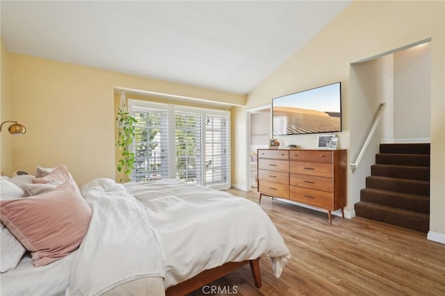 bedroom with baseboards, light wood-style floors, and vaulted ceiling
