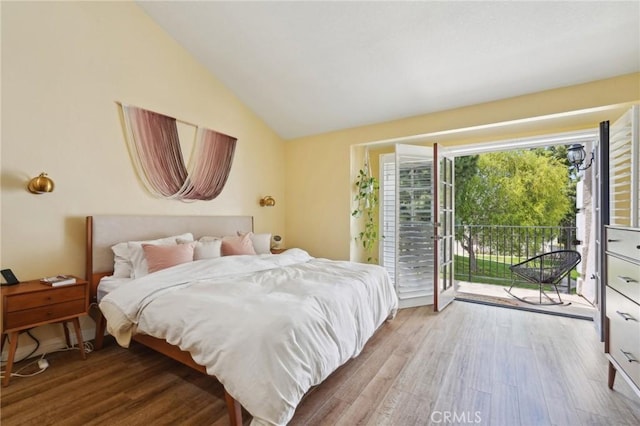 bedroom featuring access to exterior, vaulted ceiling, and wood finished floors