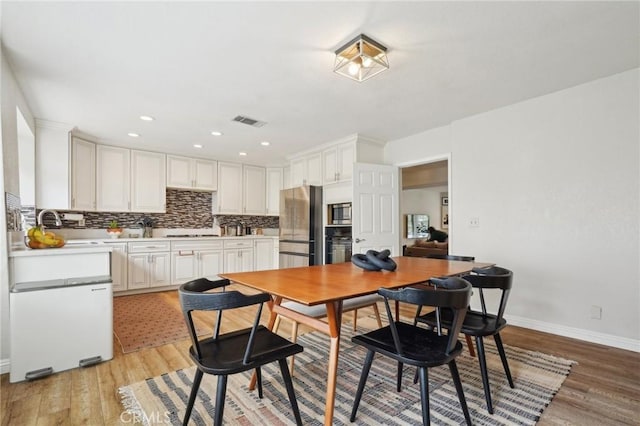 dining room featuring light wood finished floors, recessed lighting, visible vents, and baseboards