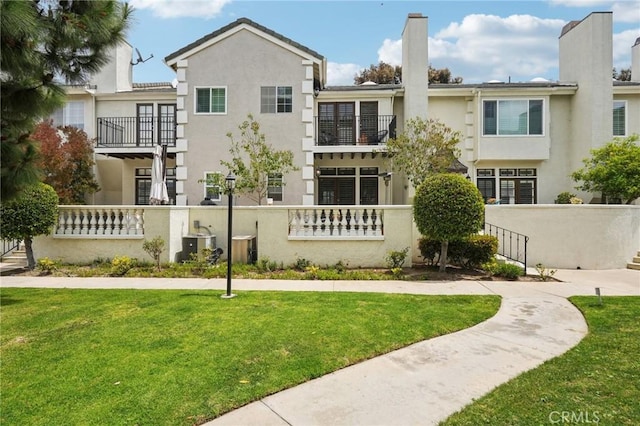 rear view of house with fence, stucco siding, and a balcony