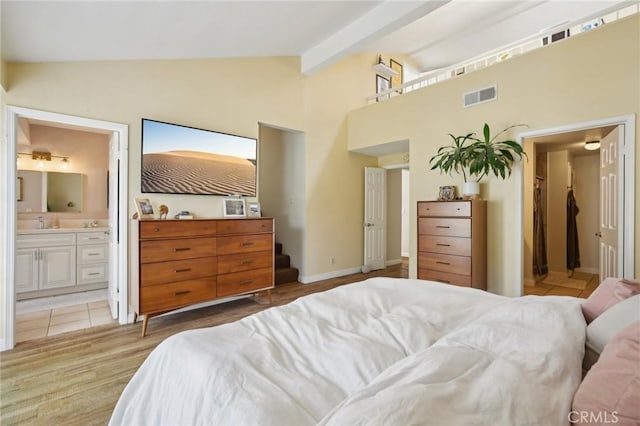 bedroom featuring connected bathroom, beamed ceiling, a sink, visible vents, and high vaulted ceiling