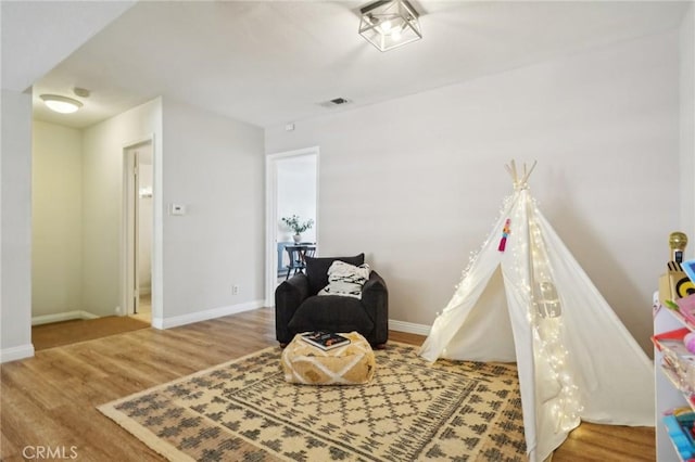 playroom with wood finished floors, visible vents, and baseboards