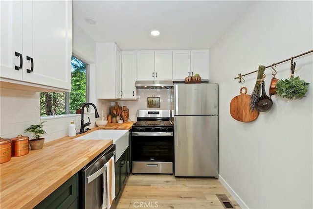 377 Hillside Rd, Lake Arrowhead, CA 92352 - kitchen featuring stainless steel appliances, under cabinet range hood, wooden counters, white cabinetry, and backsplash