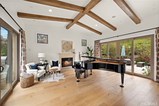 living area with french doors, a glass covered fireplace, a healthy amount of sunlight, and vaulted ceiling with beams