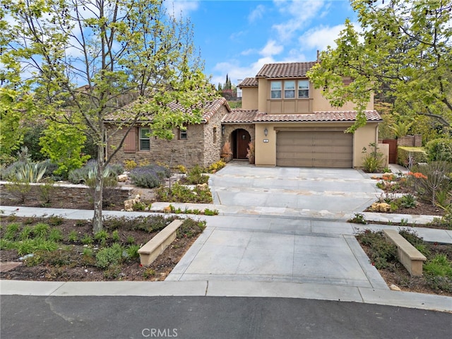 mediterranean / spanish-style home featuring stone siding, stucco siding, concrete driveway, an attached garage, and a tile roof